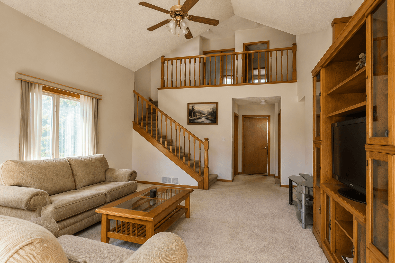 A 1990s home interior with vaulted ceiling and oak staircase, representative of the analyzed property